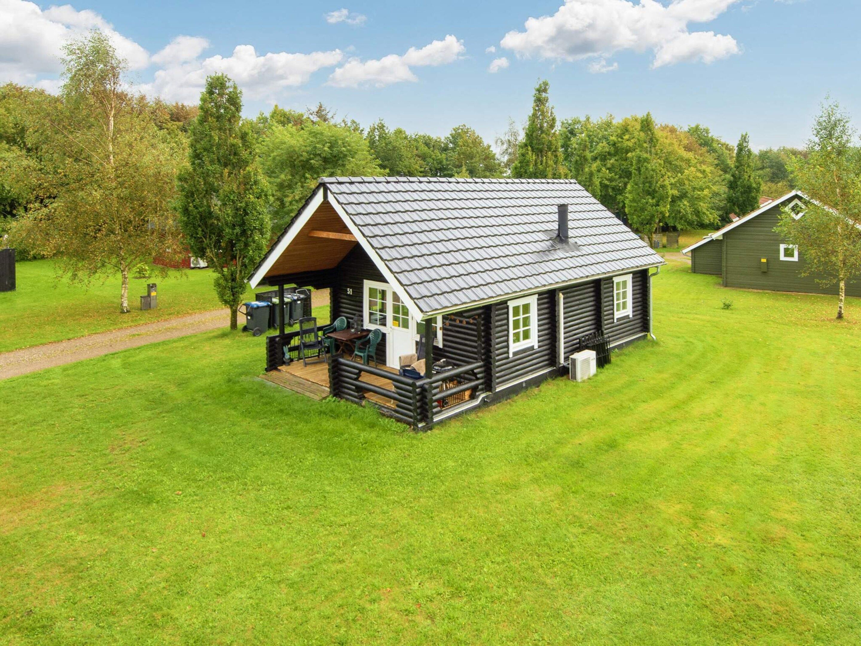 A log cabin with a porch, a deck, and a small attached shed.