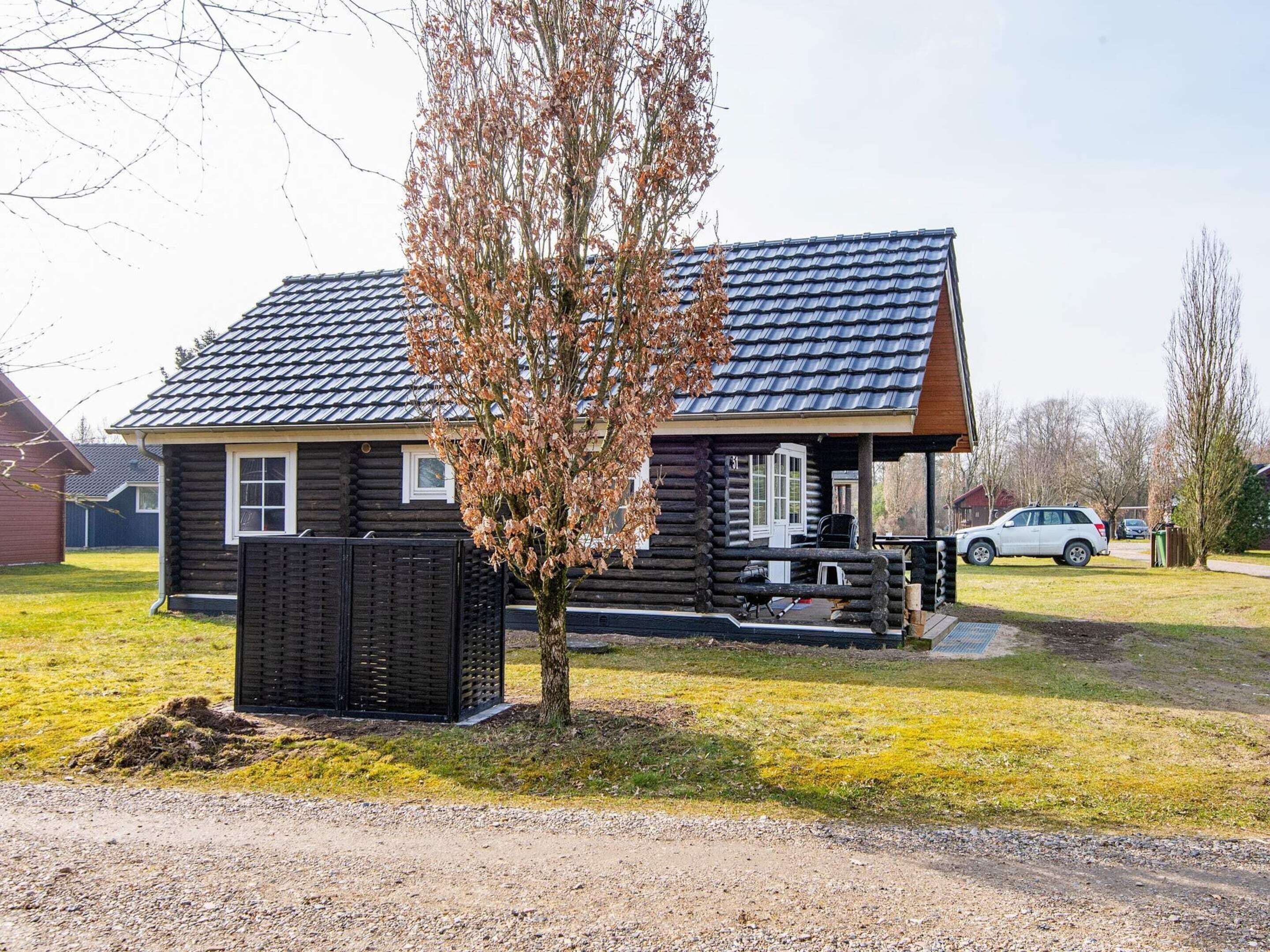 A log cabin with a sloped roof, a small porch, and a fenced yard.