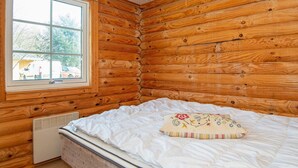 A log cabin room with a bed, a window, and a radiator. - 4 Person Holiday Home in Hovborg-by Traum (Hovborg)