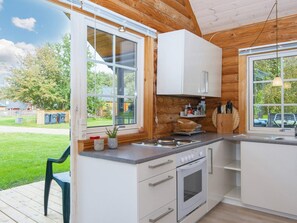 A modern kitchen with white cabinets, a built-in oven, and a large window offering a view of the outdoors. - 4 Person Holiday Home in Hovborg (Hovborg)