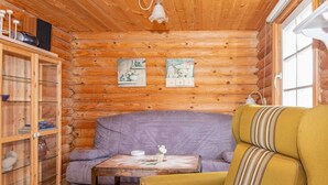 A cozy cabin interior with a wooden log wall, a purple sofa, a yellow armchair, and a small table with a teapot and cup. - 4 Person Holiday Home in Hovborg-by Traum (Hovborg)