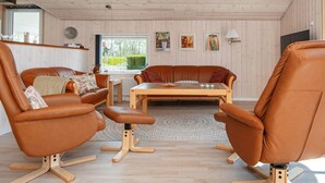 A modern living room with leather sofas, a wooden coffee table, and a view of the outdoors through a large window. - 8 Person Holiday Home in Hejls-by Traum (Hejls)