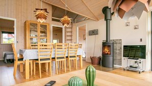 A cozy living room with a wooden dining area, a fireplace, and a television. - 5 Star Holiday Home in Lemvig (Lemvig)