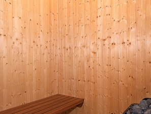 Uma sauna de madeira com um banco e aquecedor de pedra.