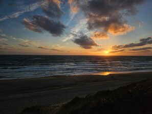 A beach with waves, a sunset, and a clear sky.