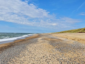 A beach with pebbles and sand, a clear sky, and distant hills. - 5 Star Holiday Home in Ulfborg (Ulfborg)