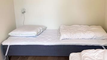 A single bed with a mattress, pillows, and a blanket.