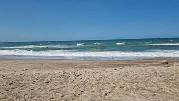 A sandy beach with waves, clear sky, and no visible structures.