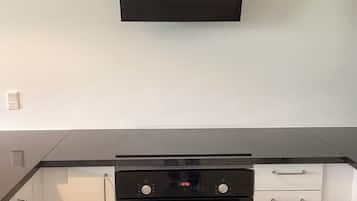 Una cocina con estufa negra, armarios blancos y encimera negra.