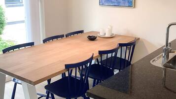 A dining area with a wooden table, blue chairs, a small bowl, and two candles on a plate.