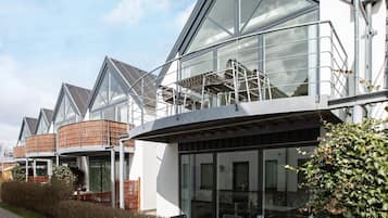 Un edificio moderno con amplios ventanales, una zona de estar al aire libre techada y una estructura de ladrillo.