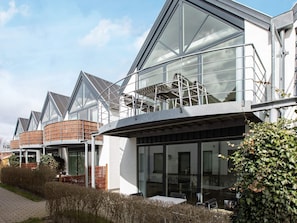 A modern building with large glass windows, a covered outdoor seating area, and a brick structure. - 4 Star Holiday Home in Vaeggerlose (Vaeggerlose)