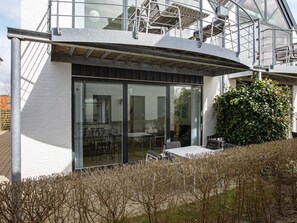 A modern building with a glass facade, outdoor seating area, and a staircase leading to an upper level. - 4 Star Holiday Home in Vaeggerlose (Vaeggerlose)