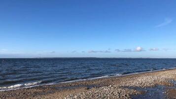 A beach with pebbles and calm water.