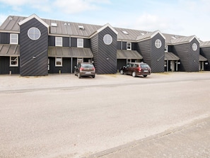A row of identical buildings with a central entrance and a parking area in front.