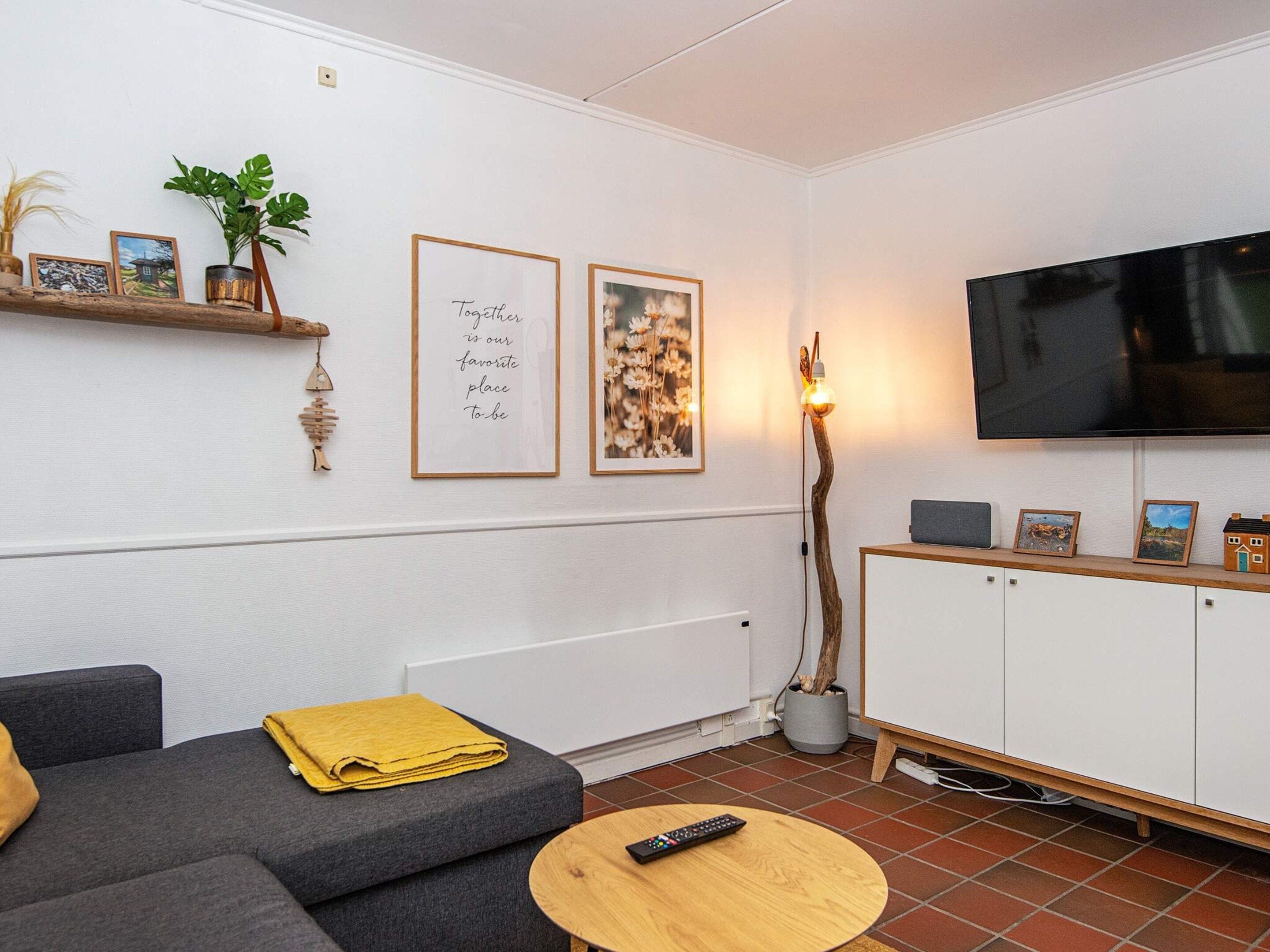 A modern living room with a sofa, a coffee table, a TV, and framed pictures on the wall.