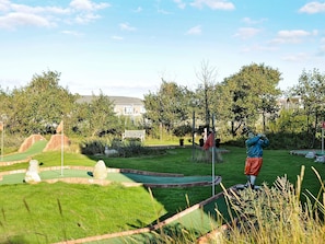 En minigolfbane med en golfspillers statue, en bænk og et flag.
