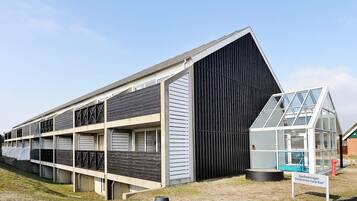 A building with a modern design, featuring a large glass structure and a sloped roof.