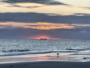 A beach with a sunset, ocean waves, and a ship in the distance. - Ravishing Apartment in Fanø Denmark near Sea (Fano)