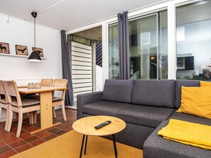 A modern living room with a grey sofa, wooden dining table, and chairs. - Ravishing Apartment in Fanø Denmark near Sea (Fano)