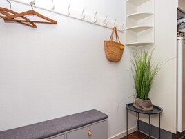 Ein Zimmer mit weißer Wand, einer grauen Bank, einem hängenden Korb und einem Topfpflanzen.