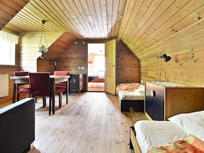 A cozy attic room with a wooden ceiling, a dining table with chairs, a bed, and a desk with a lamp. - 8 Person Holiday Home in Lonsboda (Lönsboda)