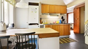 A kitchen with wooden cabinets, a white refrigerator, and a dining area with a table and chairs. - 8 Person Holiday Home in Lonsboda (Lönsboda)