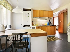A kitchen with wooden cabinets, a white refrigerator, and a dining area with a table and chairs. - 8 Person Holiday Home in Lonsboda (Lönsboda)