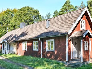 A red wooden house with a sloped roof, white window frames, and a front porch. - 8 Person Holiday Home in Lonsboda (Lönsboda)