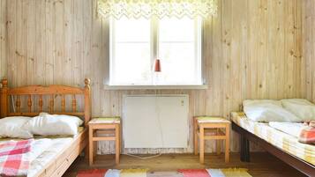 A room with two wooden beds, a radiator, and a window with a lace curtain.