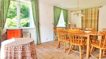 Comedor con mesa y sillas de madera, mantel estampado y ventana con cortinas.