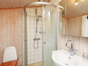 Bathroom features a glass-enclosed shower, handheld showerhead, and wall-mounted faucet.