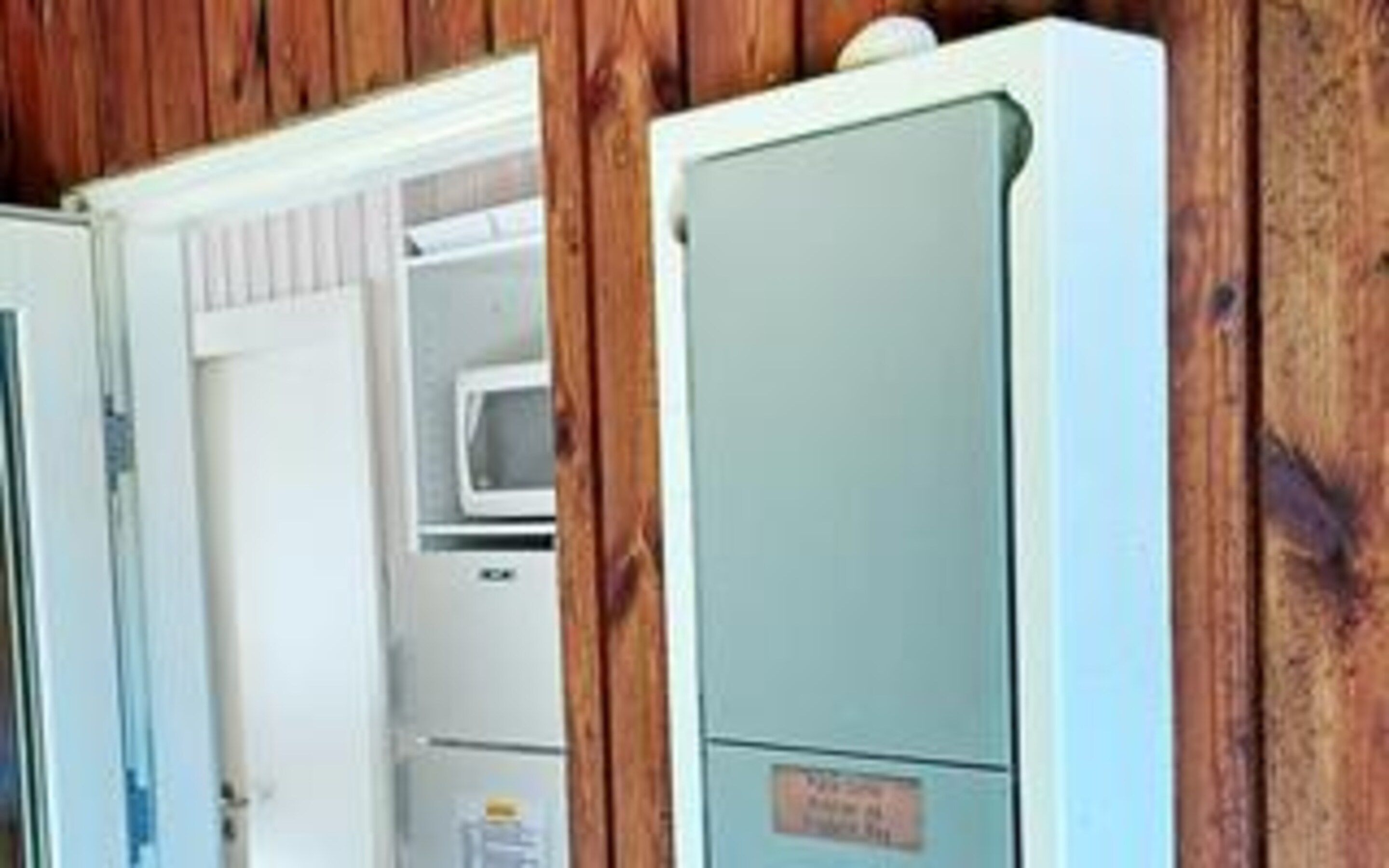 Habitación con un refrigerador blanco, un microondas y un armario con etiqueta.