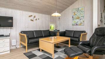 A modern living room with a sectional sofa, a coffee table, a black leather armchair, a wooden TV stand, and a mounted TV.