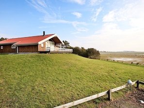A wooden house with a red roof, a porch, and a view of a grassy field. - 4 Star Holiday Home in Humble (Sydlangeland)