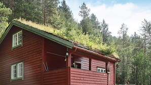 Una baita di legno rossa con tetto verde, circondata da alberi.