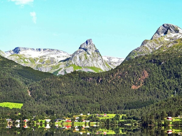 A mountainous landscape with a lake reflecting buildings and houses.