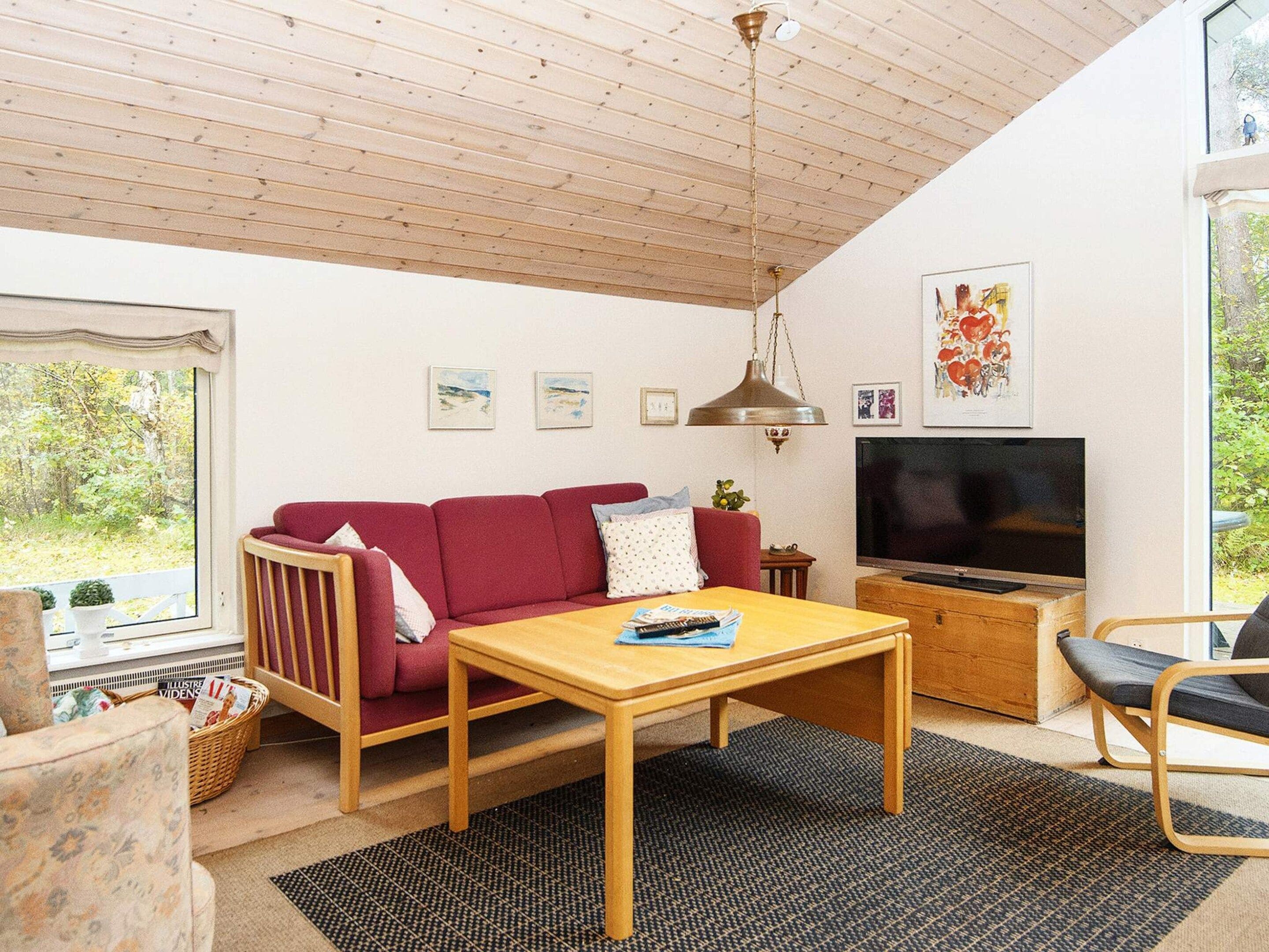 A cozy living room with a red sofa, wooden coffee table, and a television.
