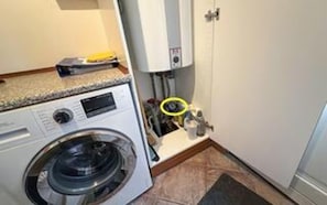 A compact laundry area with a washing machine, a dryer, and a small cabinet with a control panel.
