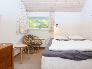 A bedroom with a bed, a chair, a dresser, and a window with curtains. - 5 Star Holiday Home in Grenaa (Grenaa)
