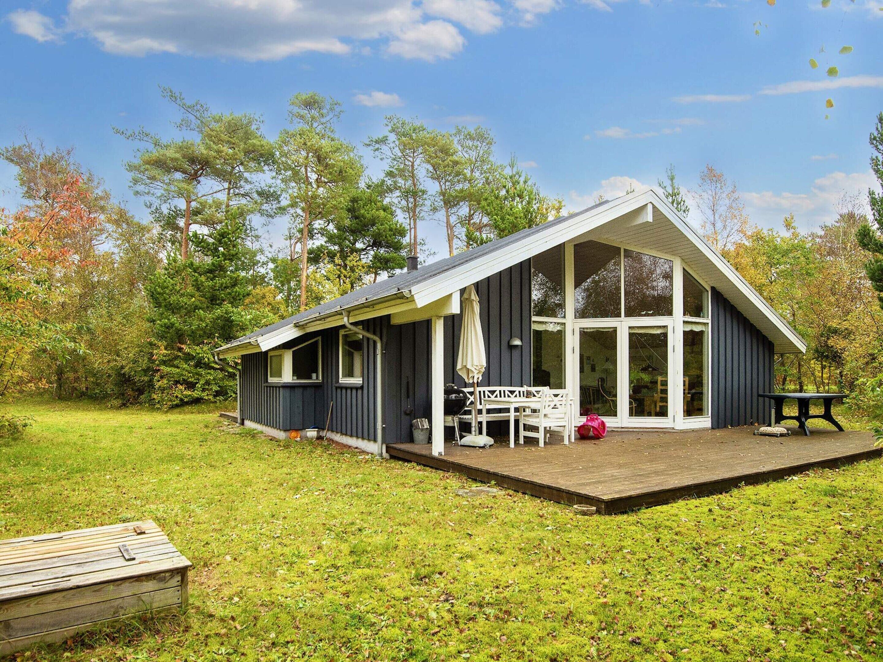 A single-story house with a covered porch, a dining table, and a bench.