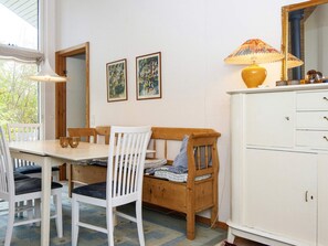 A room with a dining table, chairs, a bench, a cabinet, and two framed pictures on the wall. - 5 Star Holiday Home in Grenaa (Grenaa)