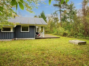 A house with a deck, a barbecue grill, and a wooden platform.