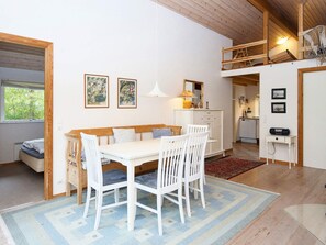 A dining area with a white table and chairs, a bench, and a hanging light fixture.
