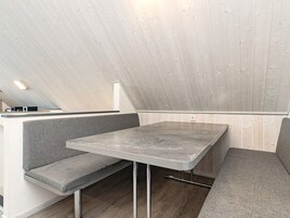 Et moderne interiør med en siddeplads med bænk, et bord og et skråt loft.