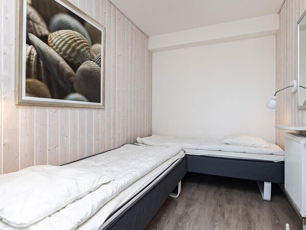 A small, compact room with two single beds, a white radiator, and a framed picture on the wall.