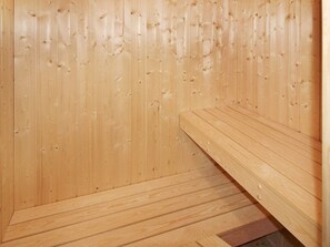 A wooden sauna with benches and a sloped floor.