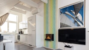 Una cocina moderna con armarios blancos, una estufa integrada y un comedor con sofás grises y una mesa blanca.