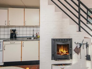 Cozinha com armários brancos, fogão preto e lareira de tijolos.