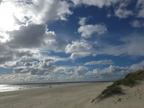A beach with a clear sky and clouds, sandy terrain, and dunes. - Cozy Holiday Home in BlÃ¥vand near Beach (Blavand)